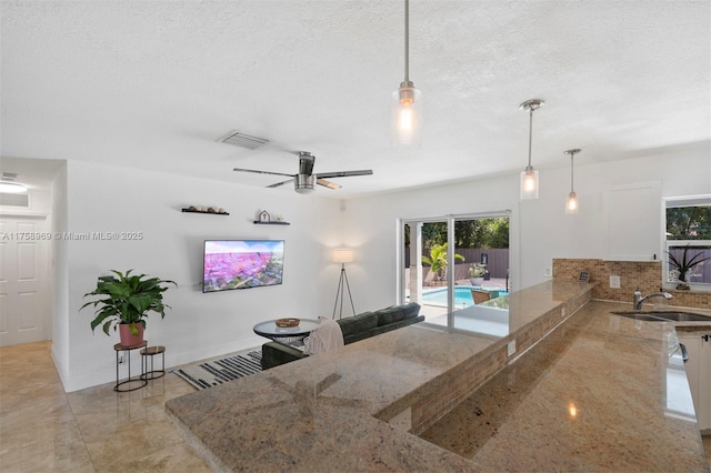 kitchen featuring pendant lighting, a textured ceiling, baseboards, and a sink