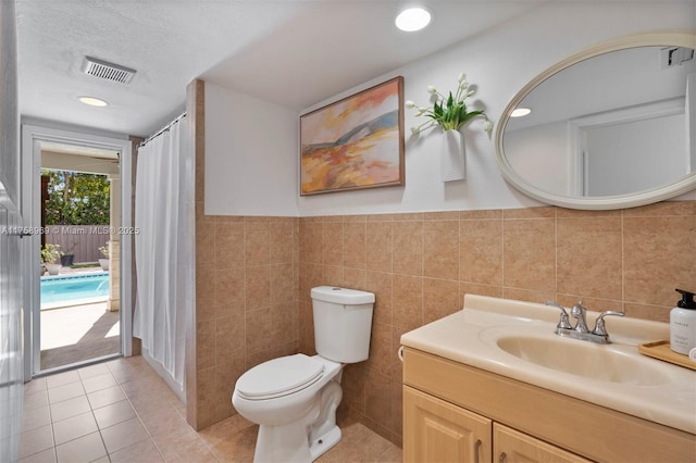 full bath with tile patterned floors, visible vents, toilet, tile walls, and vanity