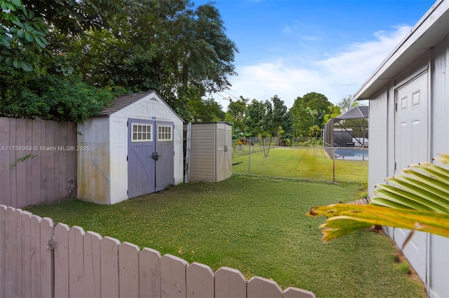 view of yard with glass enclosure, a storage shed, a fenced backyard, and an outbuilding