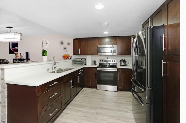 kitchen featuring a sink, light wood-style floors, appliances with stainless steel finishes, and light countertops