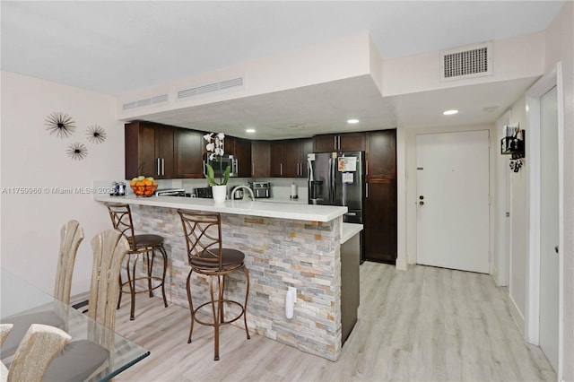 kitchen featuring visible vents, refrigerator with ice dispenser, stainless steel microwave, a peninsula, and light countertops