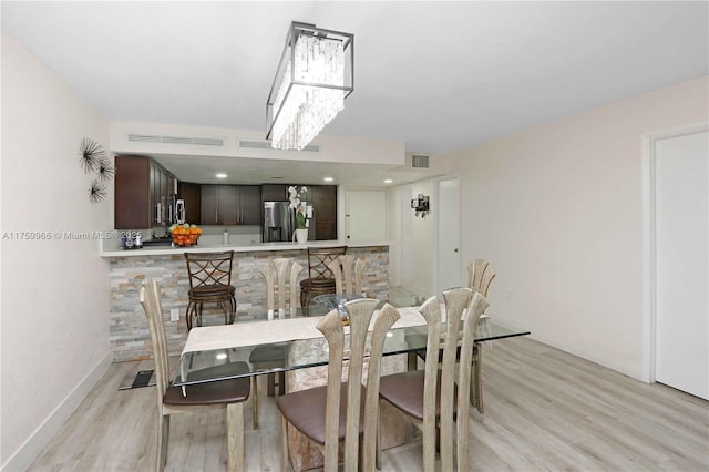 dining space with visible vents, baseboards, light wood-style floors, and an inviting chandelier