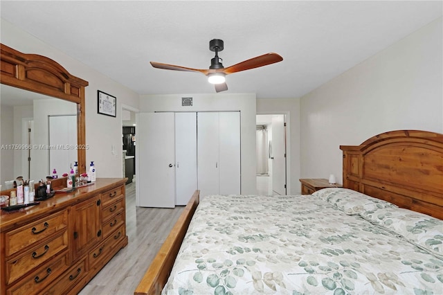 bedroom with a closet, visible vents, light wood-style flooring, and a ceiling fan