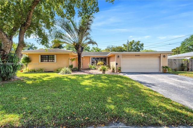 ranch-style home featuring a front yard, fence, an attached garage, stucco siding, and aphalt driveway