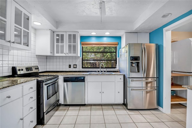 kitchen with backsplash, appliances with stainless steel finishes, white cabinetry, and a sink