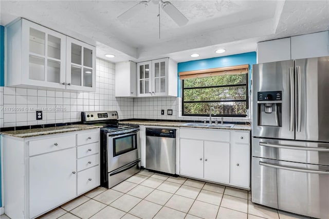 kitchen featuring a sink, dark stone countertops, backsplash, stainless steel appliances, and white cabinets