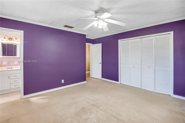 unfurnished bedroom featuring visible vents, light carpet, ornamental molding, ensuite bathroom, and a closet