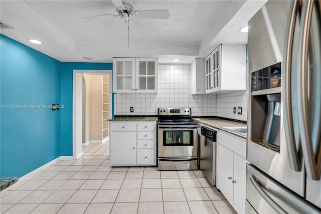 kitchen featuring light tile patterned floors, stainless steel appliances, decorative backsplash, white cabinets, and dark countertops