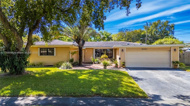 ranch-style house featuring fence, aphalt driveway, a front yard, stucco siding, and a garage