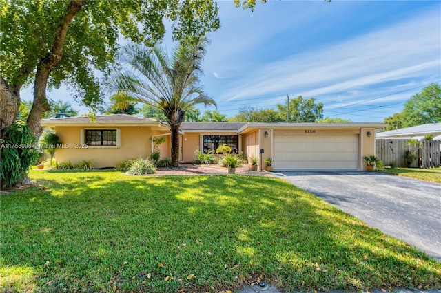 ranch-style home with fence, a front yard, stucco siding, a garage, and driveway