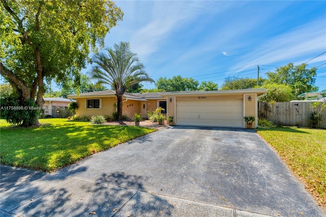 ranch-style home featuring stucco siding, driveway, fence, a front yard, and a garage