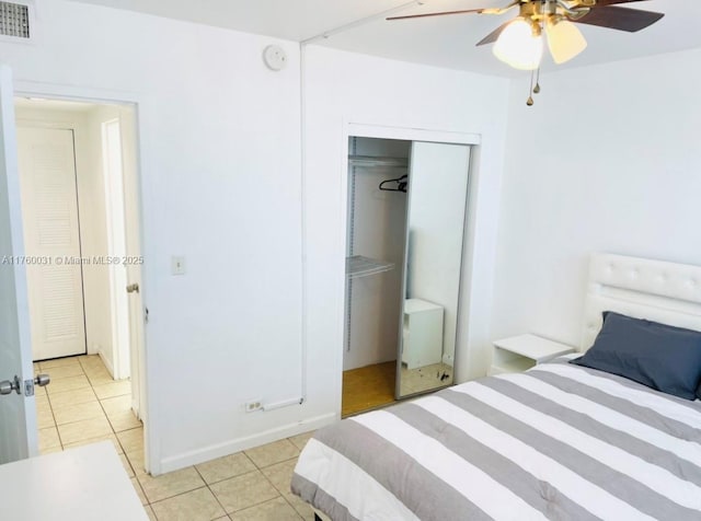 bedroom featuring light tile patterned floors, visible vents, a closet, and a ceiling fan