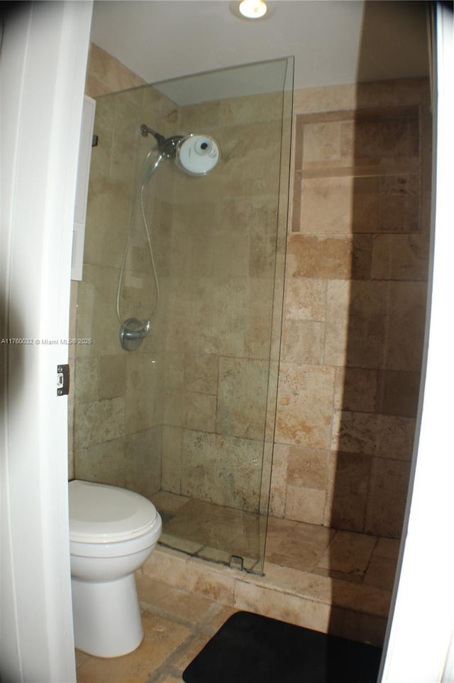 full bath featuring tiled shower and toilet