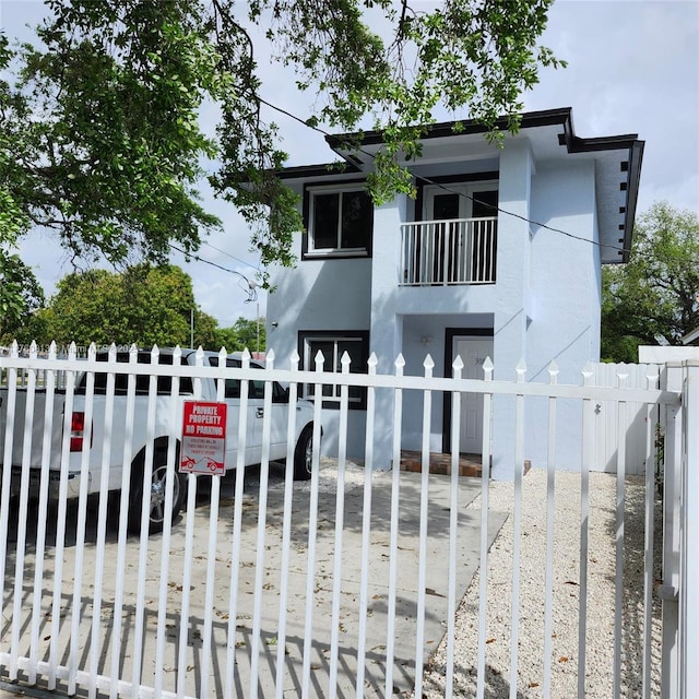 view of front of house with a gate, a fenced front yard, a balcony, and stucco siding