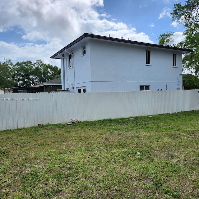 view of home's exterior with fence and a lawn