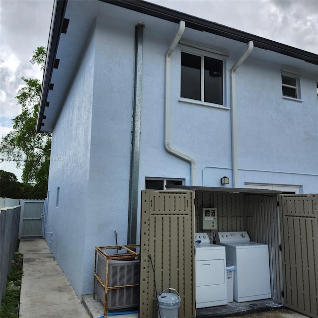 rear view of house with stucco siding, independent washer and dryer, and fence