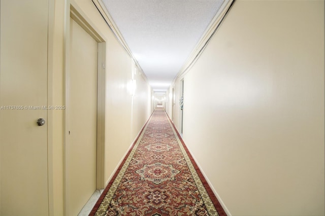 hall featuring crown molding, baseboards, and a textured ceiling