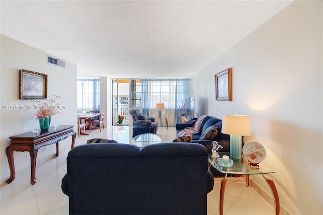 living area featuring visible vents, baseboards, floor to ceiling windows, light tile patterned floors, and a textured ceiling