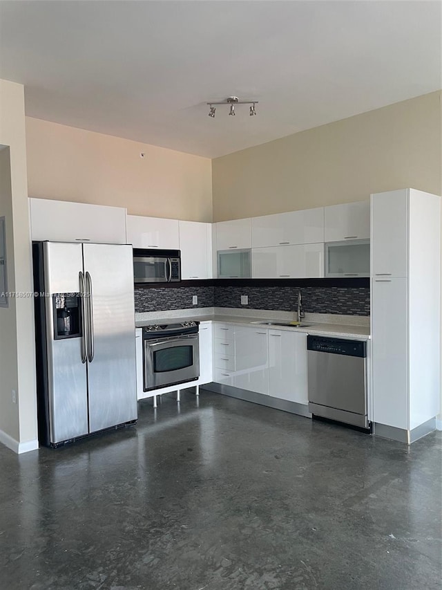 kitchen with modern cabinets, backsplash, stainless steel appliances, white cabinets, and light countertops