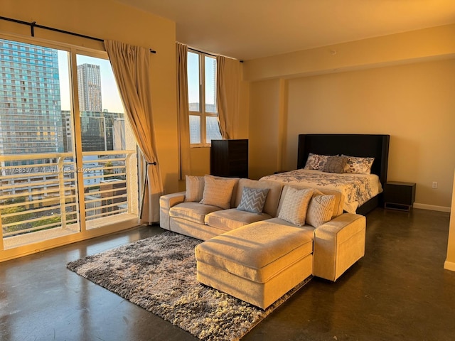 bedroom featuring a city view, baseboards, multiple windows, and concrete flooring