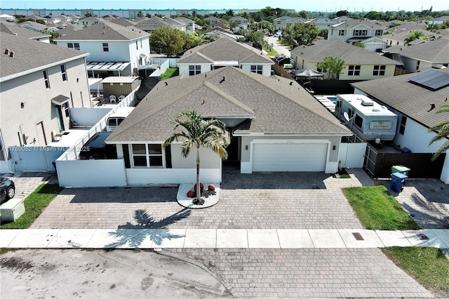 view of front of home with stucco siding, decorative driveway, a residential view, an attached garage, and fence private yard