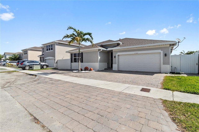 view of front of house featuring stucco siding, decorative driveway, a garage, and fence