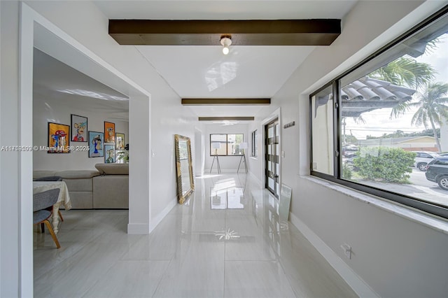 hallway with beamed ceiling and baseboards