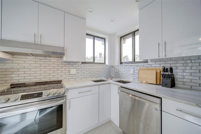 kitchen with under cabinet range hood, white cabinetry, stainless steel appliances, and light stone counters