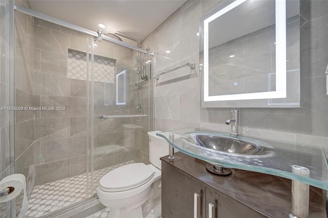 bathroom featuring a shower stall, vanity, toilet, and tile walls