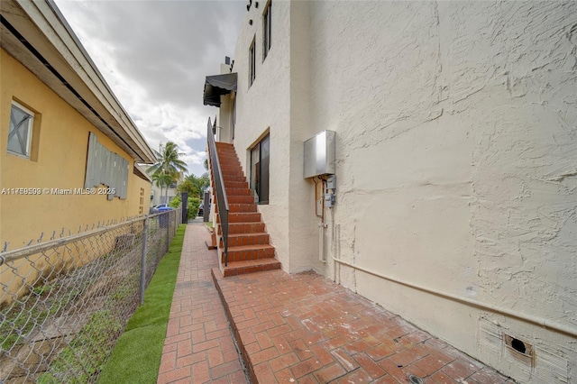 view of home's exterior with stucco siding, stairs, and fence