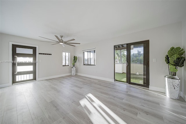 unfurnished living room featuring baseboards, light wood-type flooring, and ceiling fan