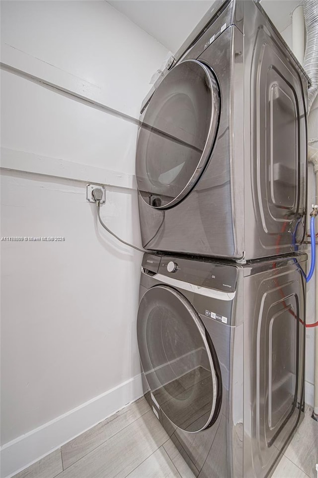 laundry area with baseboards, stacked washer and clothes dryer, and laundry area