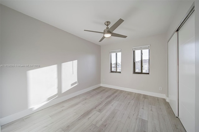 unfurnished bedroom featuring light wood-type flooring, a closet, baseboards, and ceiling fan