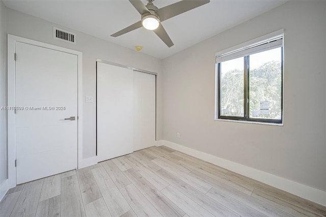 unfurnished bedroom with light wood-type flooring, visible vents, a closet, baseboards, and ceiling fan