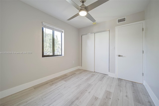 unfurnished bedroom with a closet, visible vents, light wood-type flooring, and baseboards