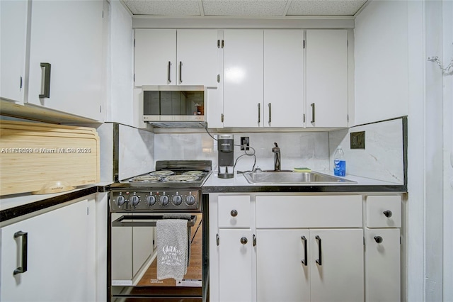 kitchen featuring a sink, a drop ceiling, white cabinetry, stainless steel appliances, and decorative backsplash