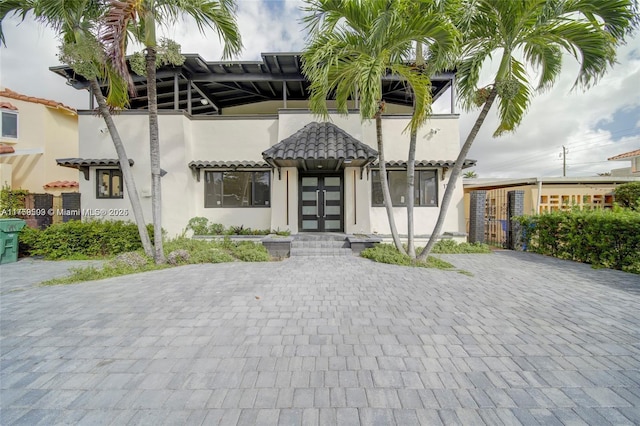 view of front of home with a tiled roof, french doors, and stucco siding