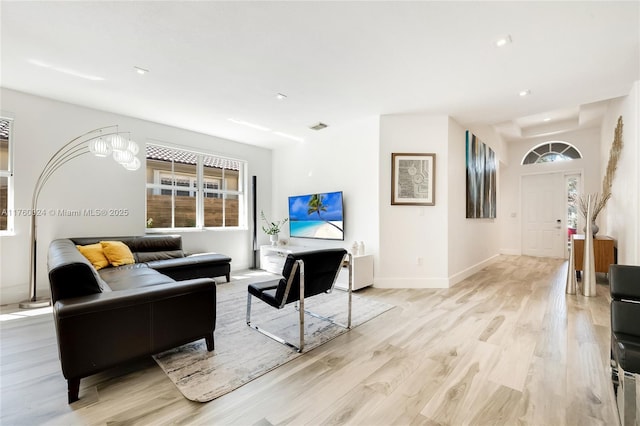 living area featuring visible vents, baseboards, and light wood finished floors