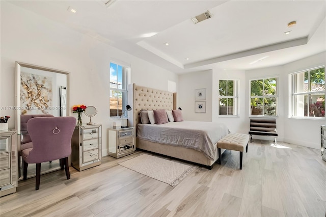 bedroom with baseboards, visible vents, recessed lighting, light wood-style floors, and a raised ceiling