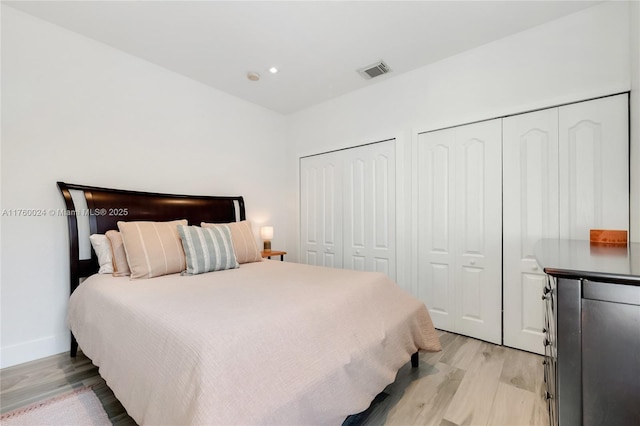 bedroom featuring visible vents, two closets, recessed lighting, light wood finished floors, and baseboards