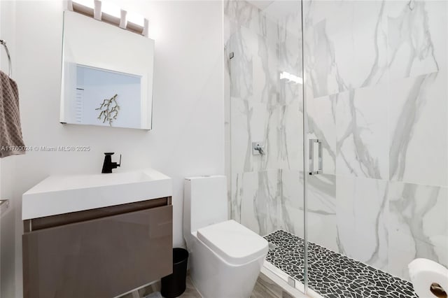 bathroom featuring a marble finish shower, toilet, and vanity