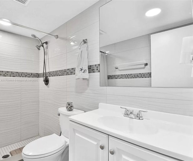 full bath featuring tiled shower, toilet, tile walls, and vanity