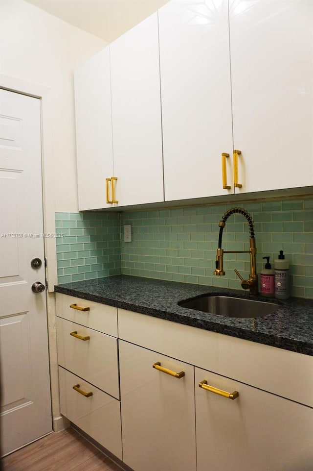 kitchen featuring a sink, light wood-style flooring, and white cabinets