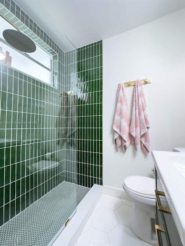 full bath featuring vanity, baseboards, tiled shower, tile patterned floors, and toilet