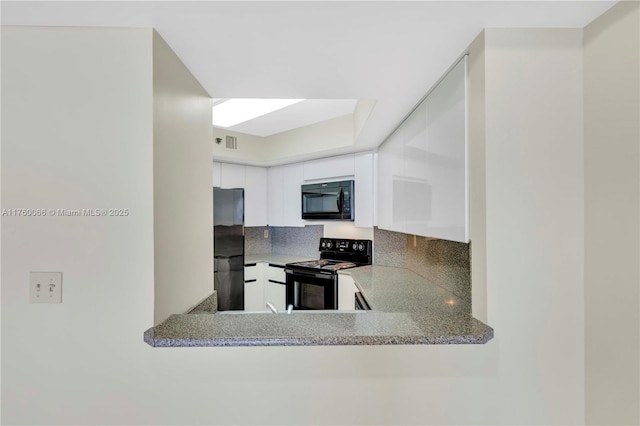 kitchen featuring visible vents, white cabinets, and black appliances