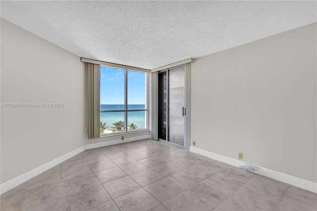 unfurnished room featuring a textured ceiling, baseboards, and a water view