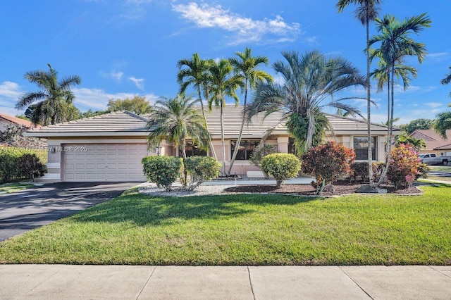 ranch-style house featuring driveway, stucco siding, a front lawn, a garage, and a tile roof