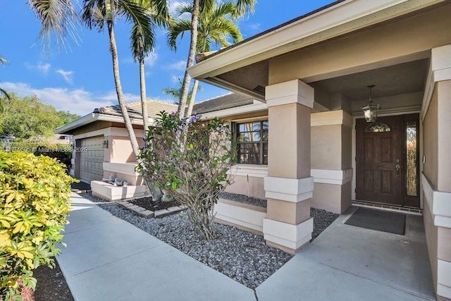 entrance to property featuring an attached garage and stucco siding