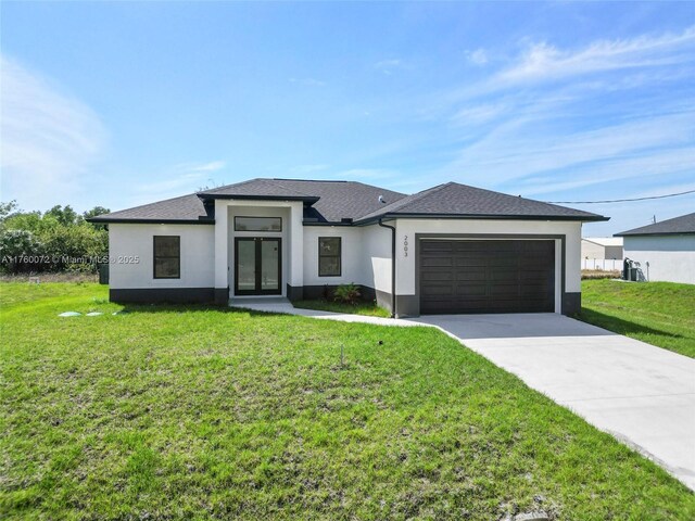 prairie-style home with stucco siding, an attached garage, concrete driveway, and a front lawn