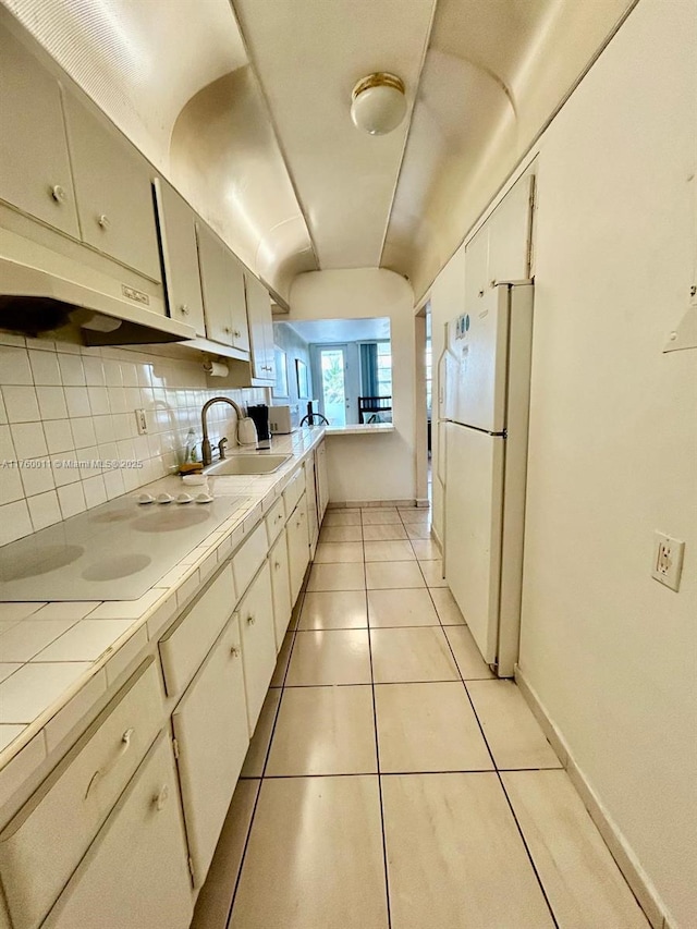 100 Lincoln Rd Unit 329, Miami Beach, FL 33139 - kitchen featuring white appliances, under cabinet range hood, tile counters, a sink, and decorative backsplash